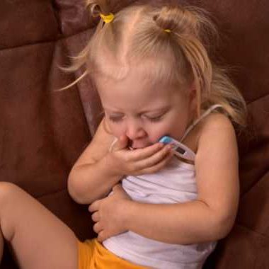 Child coughing with a thermometer under her arm.