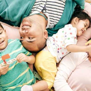 Mom and dad laying on pillows with two children.