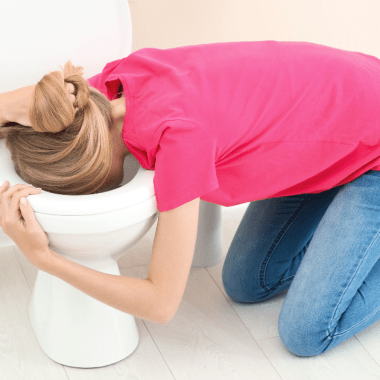 Woman vomiting over toilet - stomach virus