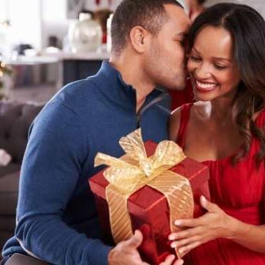 Man kissing woman's cheek and giving a gift