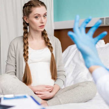 pregnant woman in front of gloved hand