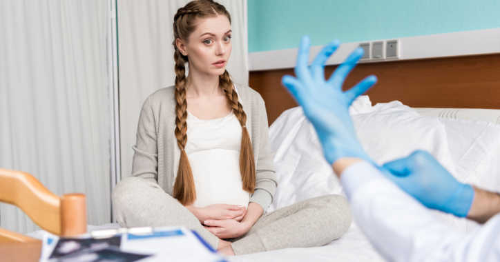 pregnant woman in front of gloved hand