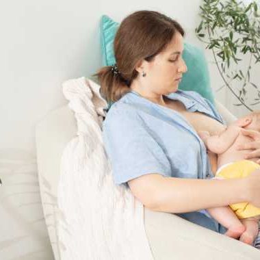 mother nursing newborn while sitting in chair