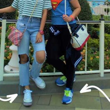 Two women standing in front of a fence at Disneyland. Arrows pointing at their feet.