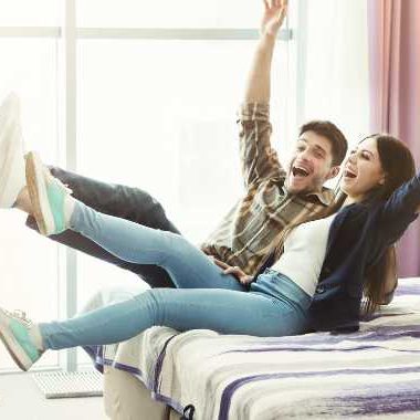 man and woman falling back onto a hotel bed