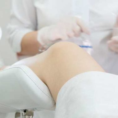 woman in stirrups, speculum in doctor's hands