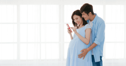 pregnant couple looking at their phone.