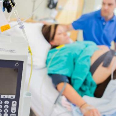 pregnant woman laying in bed with an epidural with an epidural pump in front.