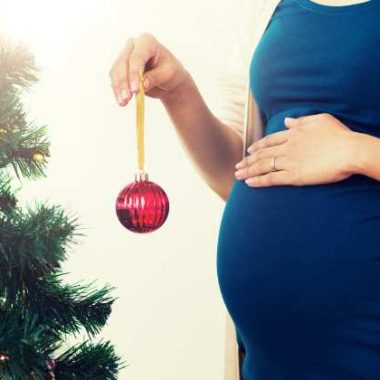 pregnant woman decorating a Christmas tree
