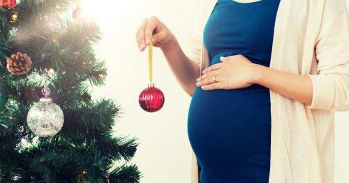 pregnant woman decorating a Christmas tree