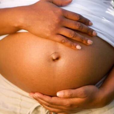 black pregnant woman holding belly, and a small sunshine.